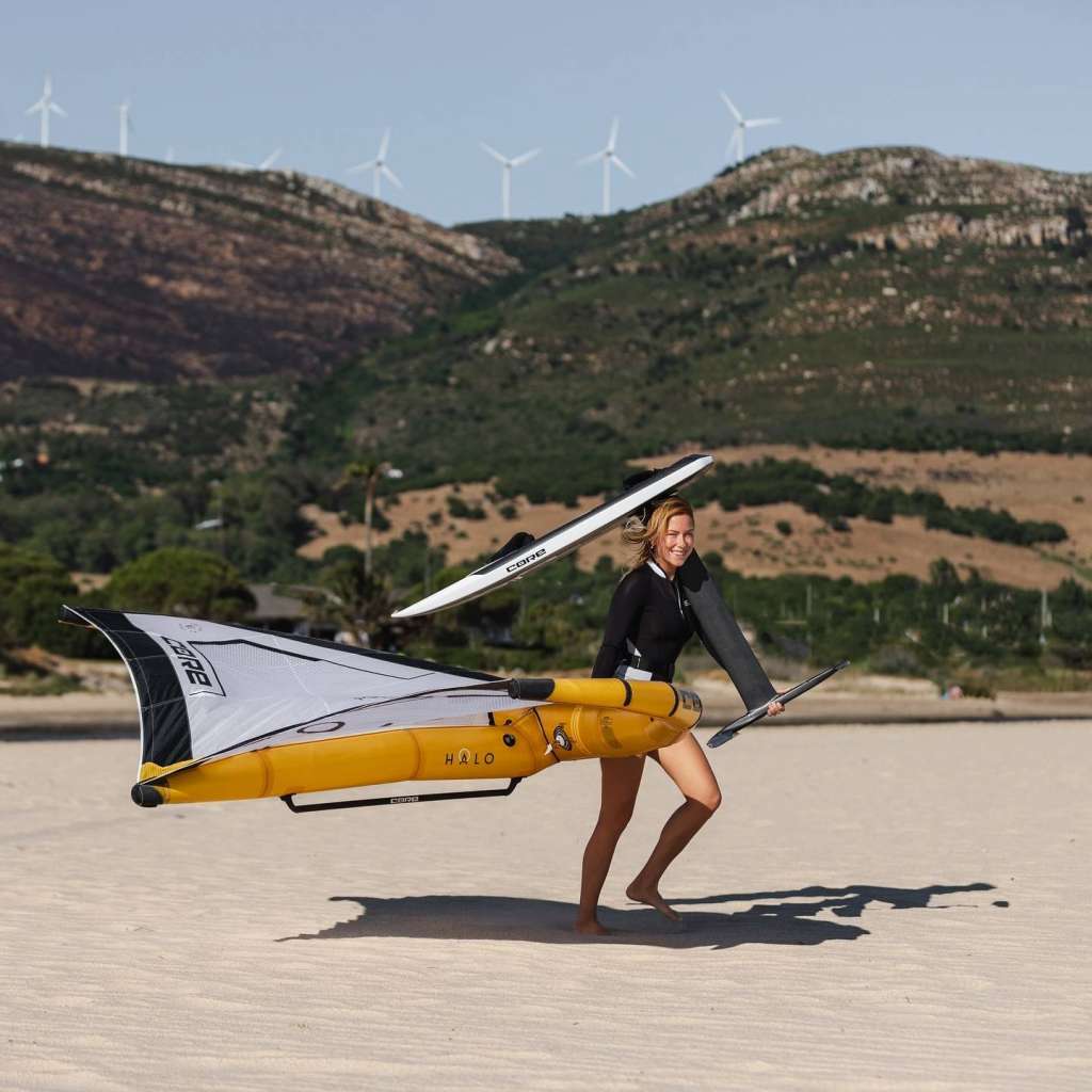Rider portant une aile CORE HALO PRO et une planche foil Core sur la plage, prête pour une session wingfoil.