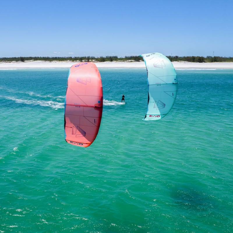 Deux ailes de kitesurf DUOTONE EVO 2025 flottant au-dessus de l'eau, avec un rider sur la mer, dans un environnement ensoleillé.