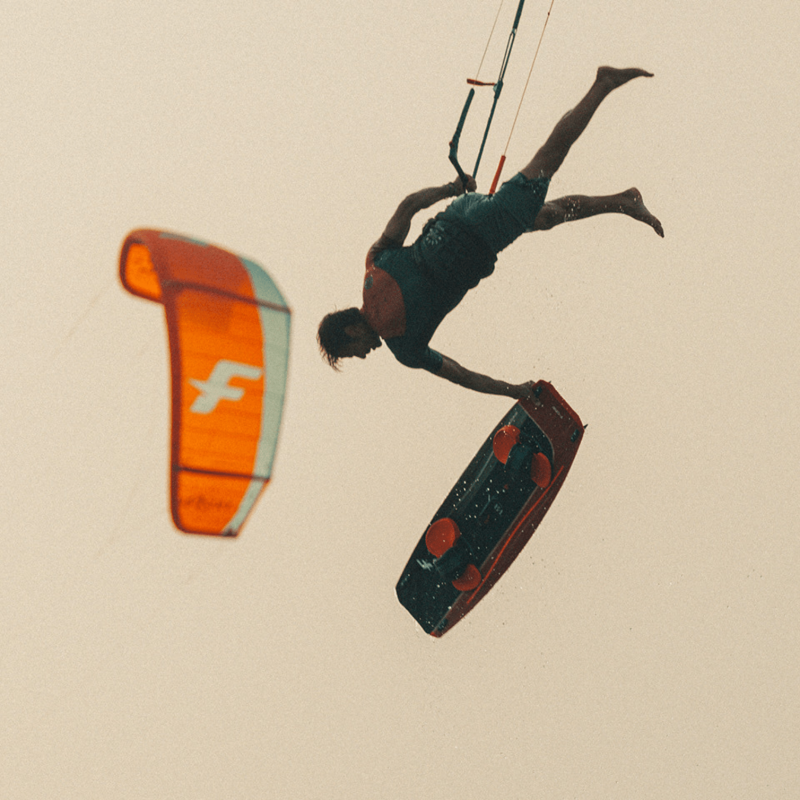Rider effectuant un trick aérien avec une planche F-ONE TRAX HRD Lite Tech 2023 en kitesurf