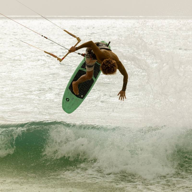 Planche surf kite Duotone Whip SLS 2026 utilisée par un kitsurfer dans un mouvement aérien, vue dynamique