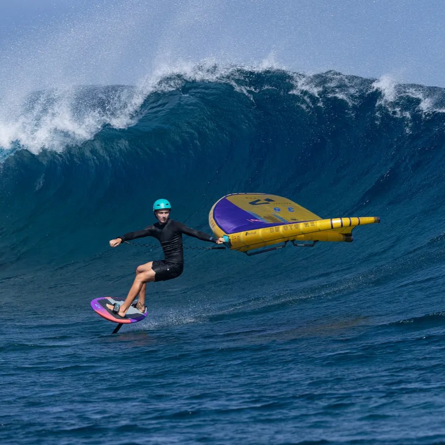 Rider en wingfoil avec aile Duotone et board Sky Surf SLS 2024 face à une grande vague à Tahiti