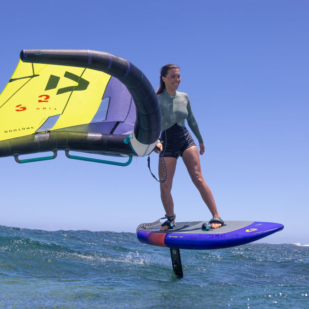 Rider en équilibre sur la planche Duotone Sky Free 2025 avec aile jaune et violette