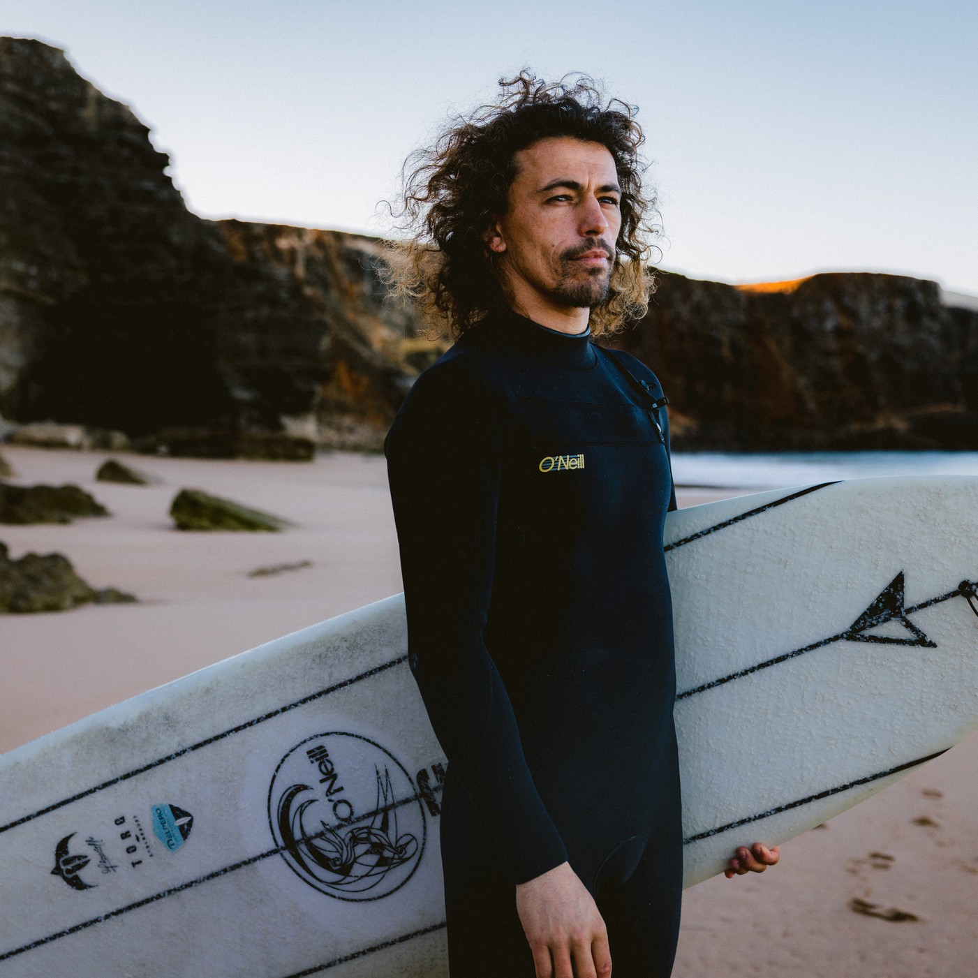 Homme portant la combinaison O'Neill Men O'Riginal RG8 3/2 mm 2025 tenant une planche de surf sur la plage