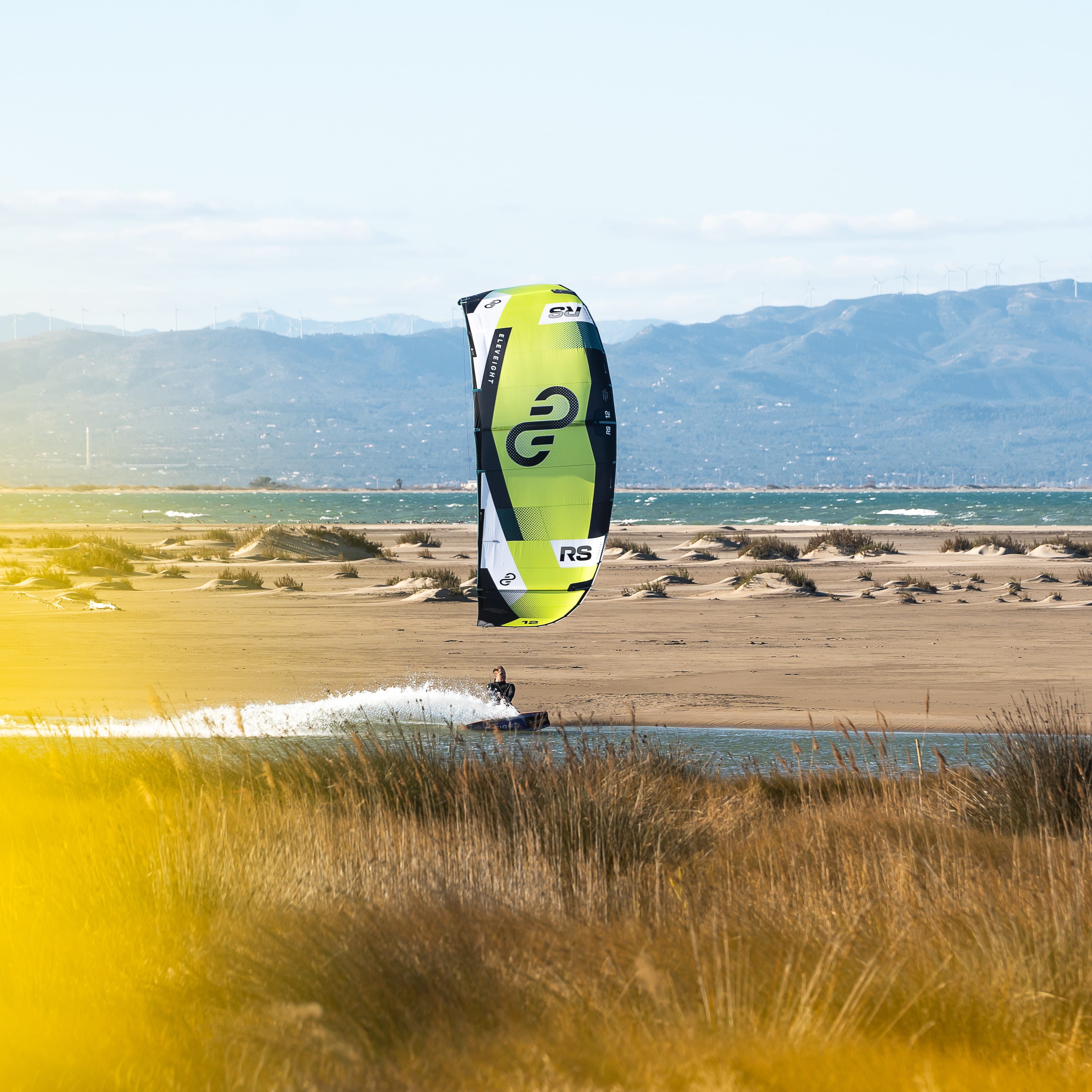 Navigation en kitesurf avec l’aile Eleveight RS V9 verte en action sur lagune et fond montagneux