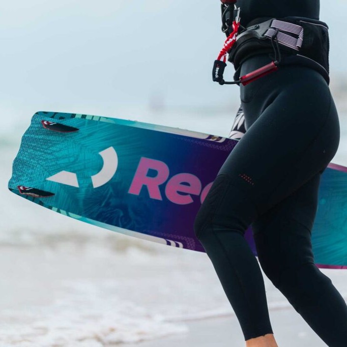 Gros plan sur la planche twin-tip Reedin GOODDAY 2025 en bord de mer