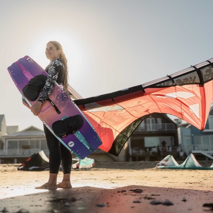 Rideuse portant la planche Reedin GOODDAY 2025 et une aile de kite Reedin sur la plage