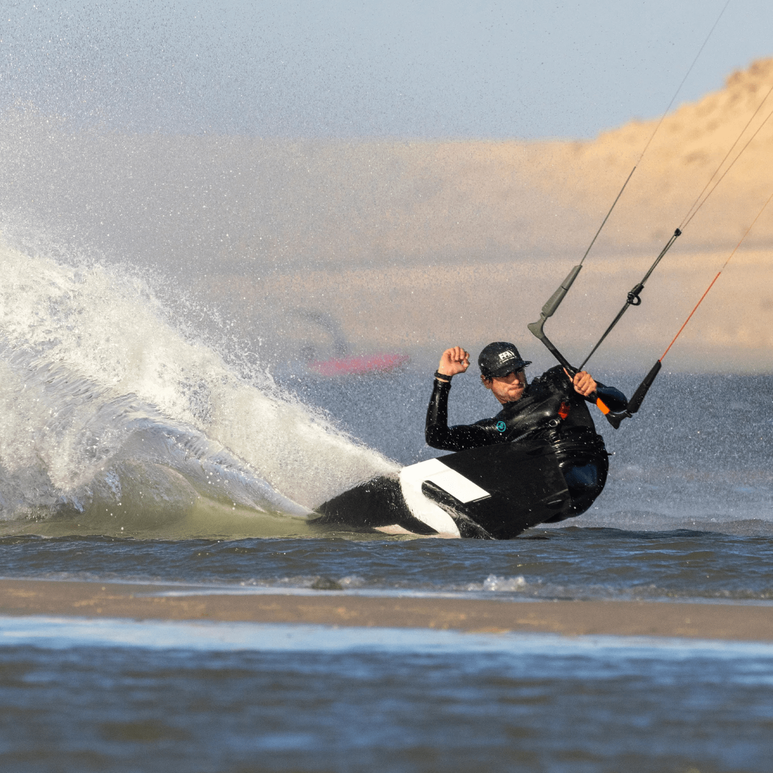 Rider en action sur planche twin-tip Slingshot ERA 2025 effectuant un virage puissant en kitesurf dans les vagues