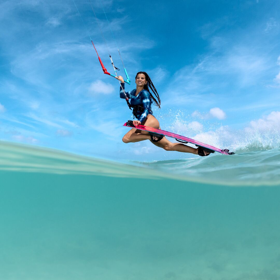 Kitesurfeuse exécutant un saut avec la planche Duotone Soleil SLS 2026, figure freestyle au-dessus des vagues.